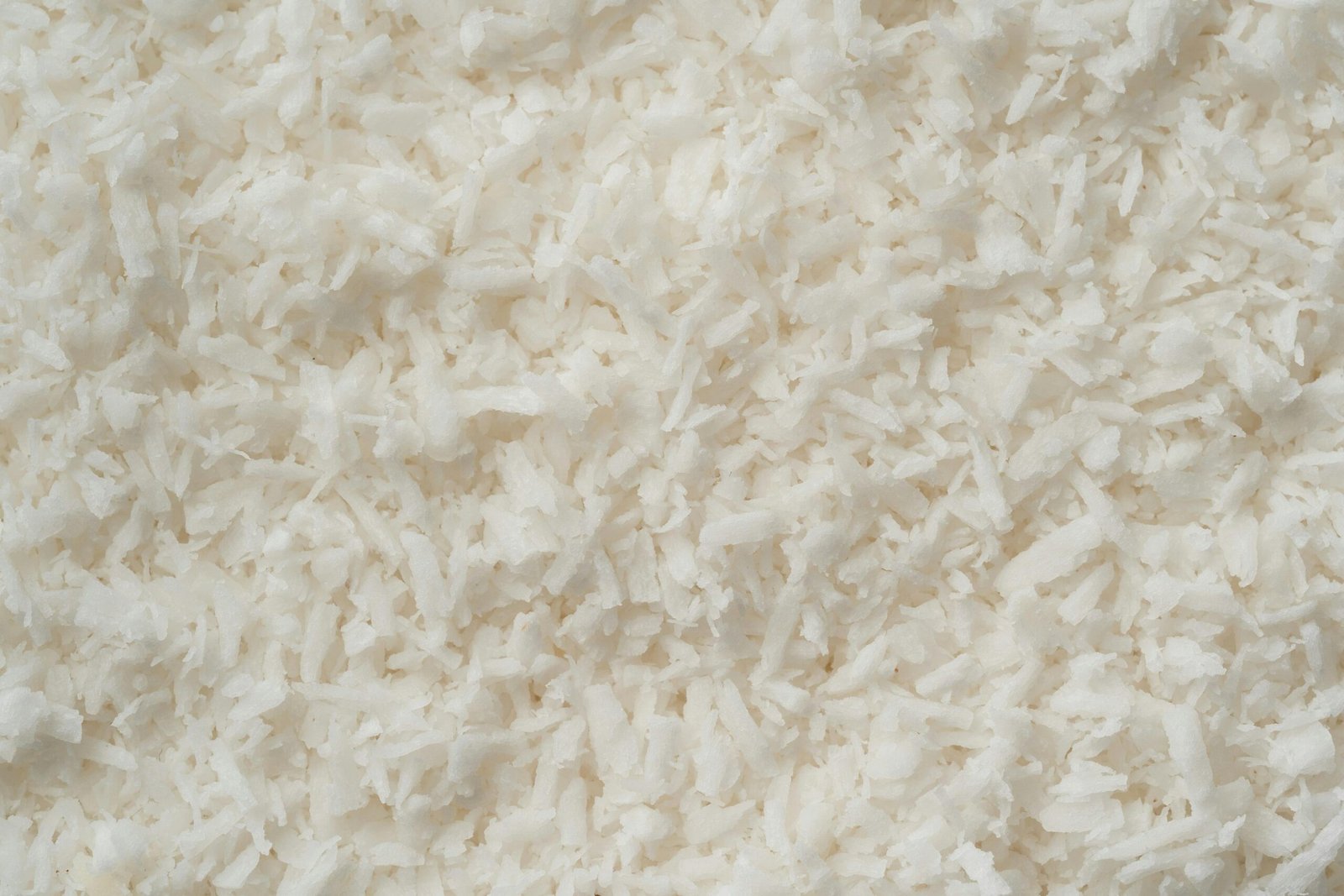 Detailed texture of fresh shredded coconut flakes, highlighting their purity and deliciousness.